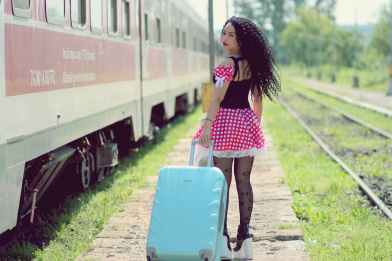 young woman with luggage standing on train in city