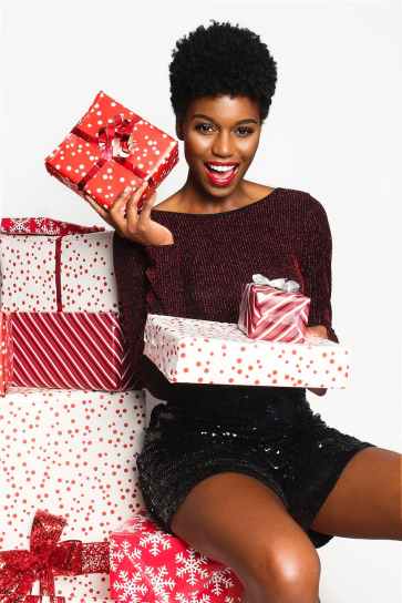woman wearing maroon long sleeved shirt and black shorts holding gift boxes