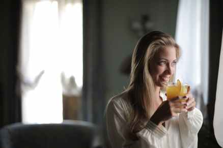 woman holding drinking glass with juice